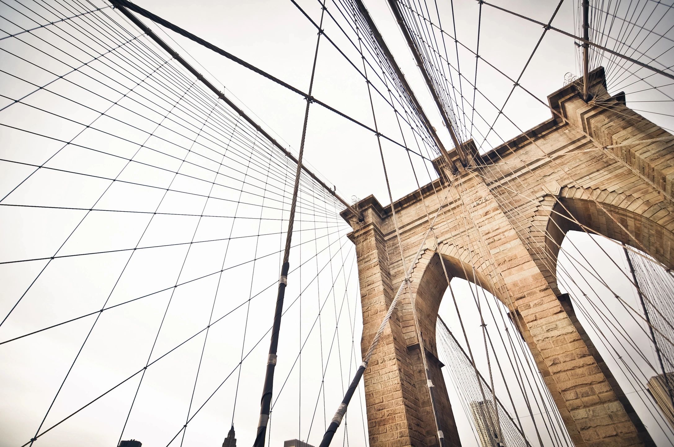 a view looking up at a bridge's arches and cables